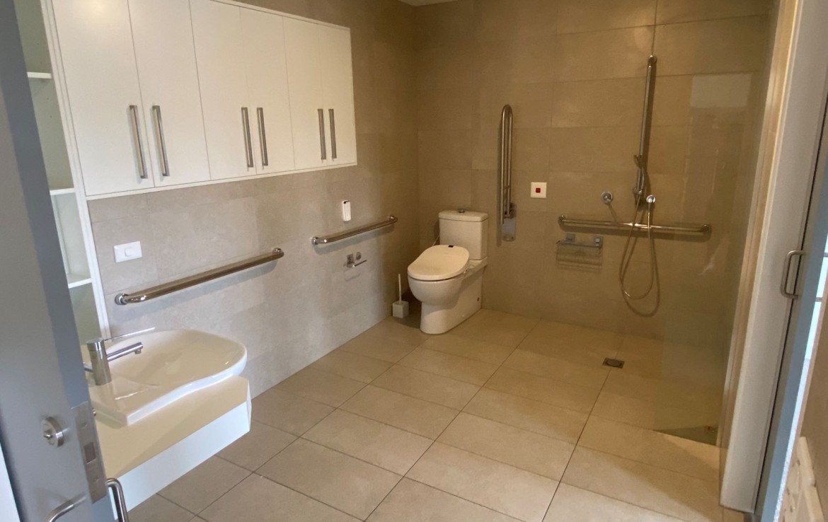 Bathroom in SDA accommodation in Richmond showing toilet, sink, shower and handrails